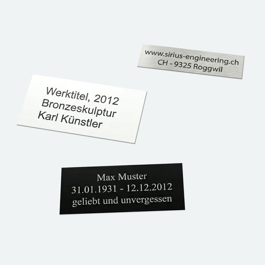 drei Schilder (silber, weiss und schwarz) aus Kunststoff mit Text